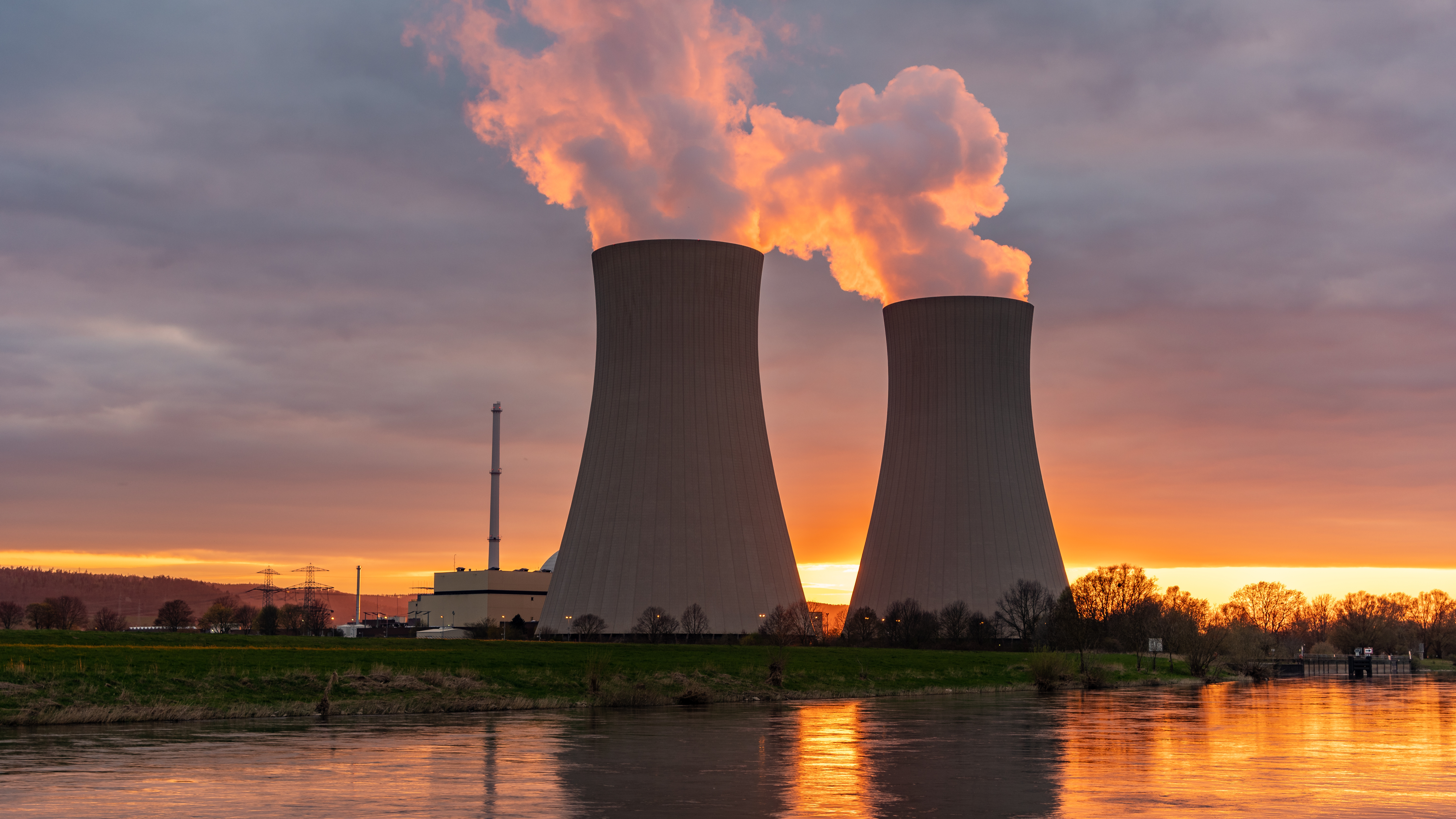 Nuclear power plant against sky by the river at sunset